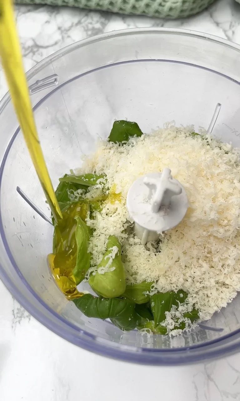 adding olive oil to pesto.