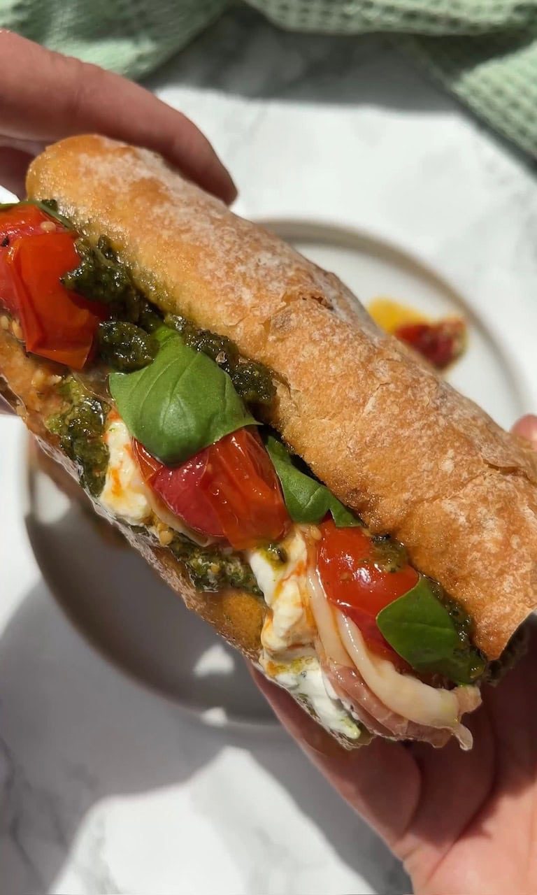 woman holding burrata caprese sandwich.