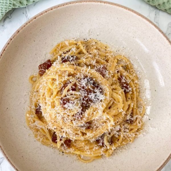 carbonara with guanciale in a beige bowl