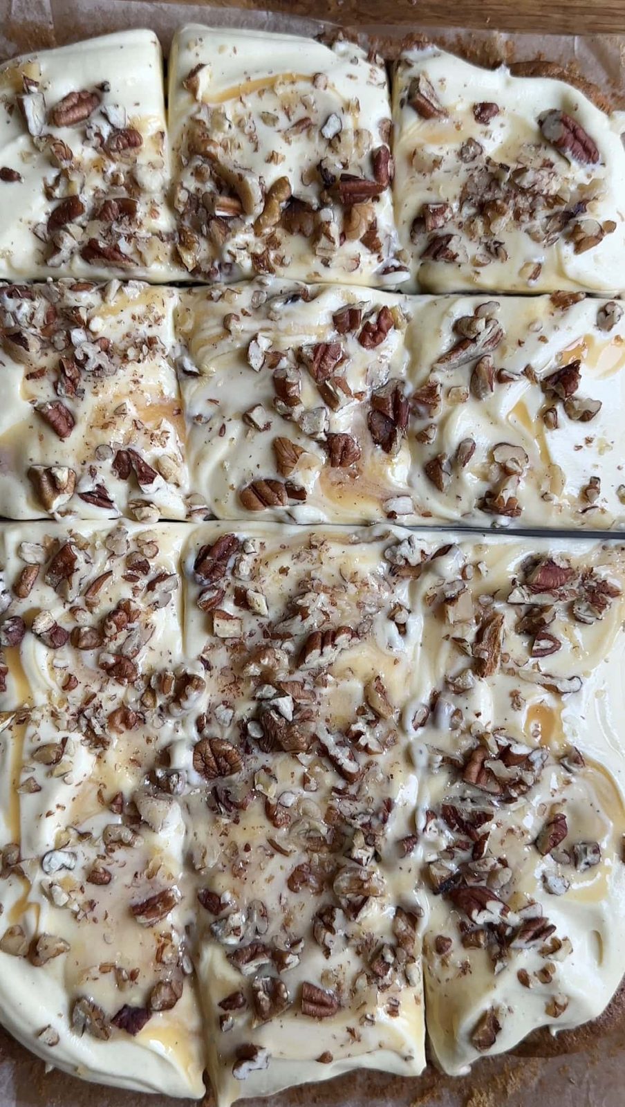 carrot cake tray bake. covered with icing with a knife cutting through.