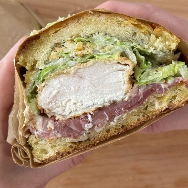 Woman holding half of a chicken caesar sandwich