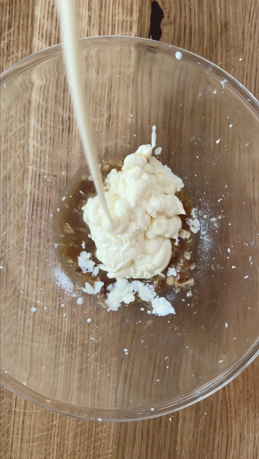 adding mayo to garlic and anchovy in a glass bowl