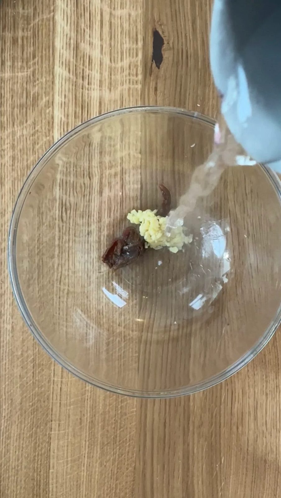 adding boiling water to garlic and anchovy in a glass bowl