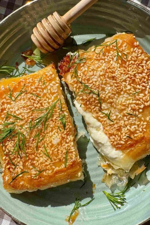 feta saganaki cut in half on a green plate with honey and dill.