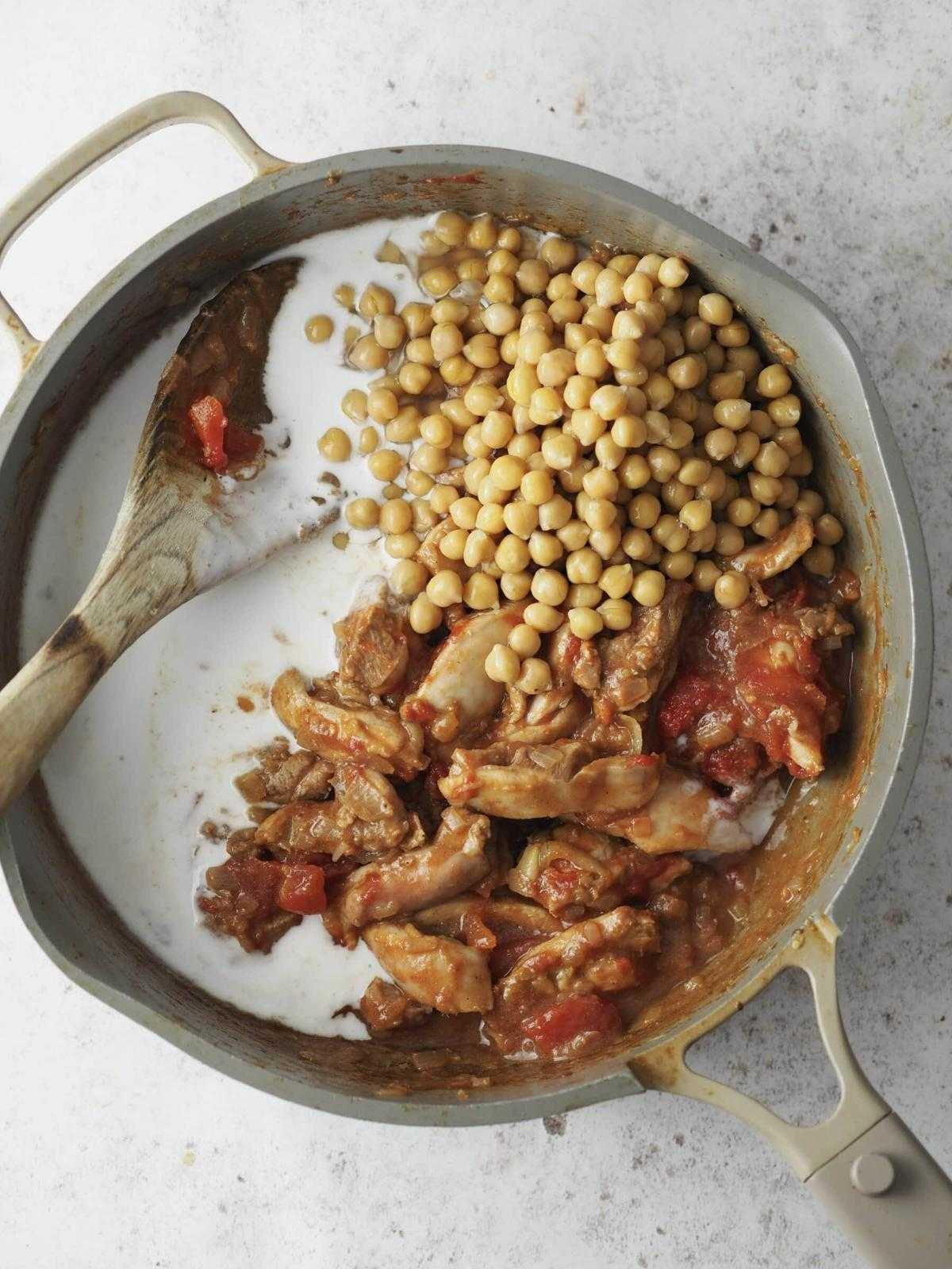stirring the chicken and chickpea curry together.