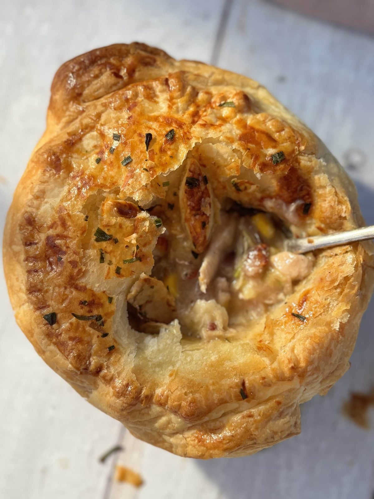 Mini chicken pot pie with spoon on table.