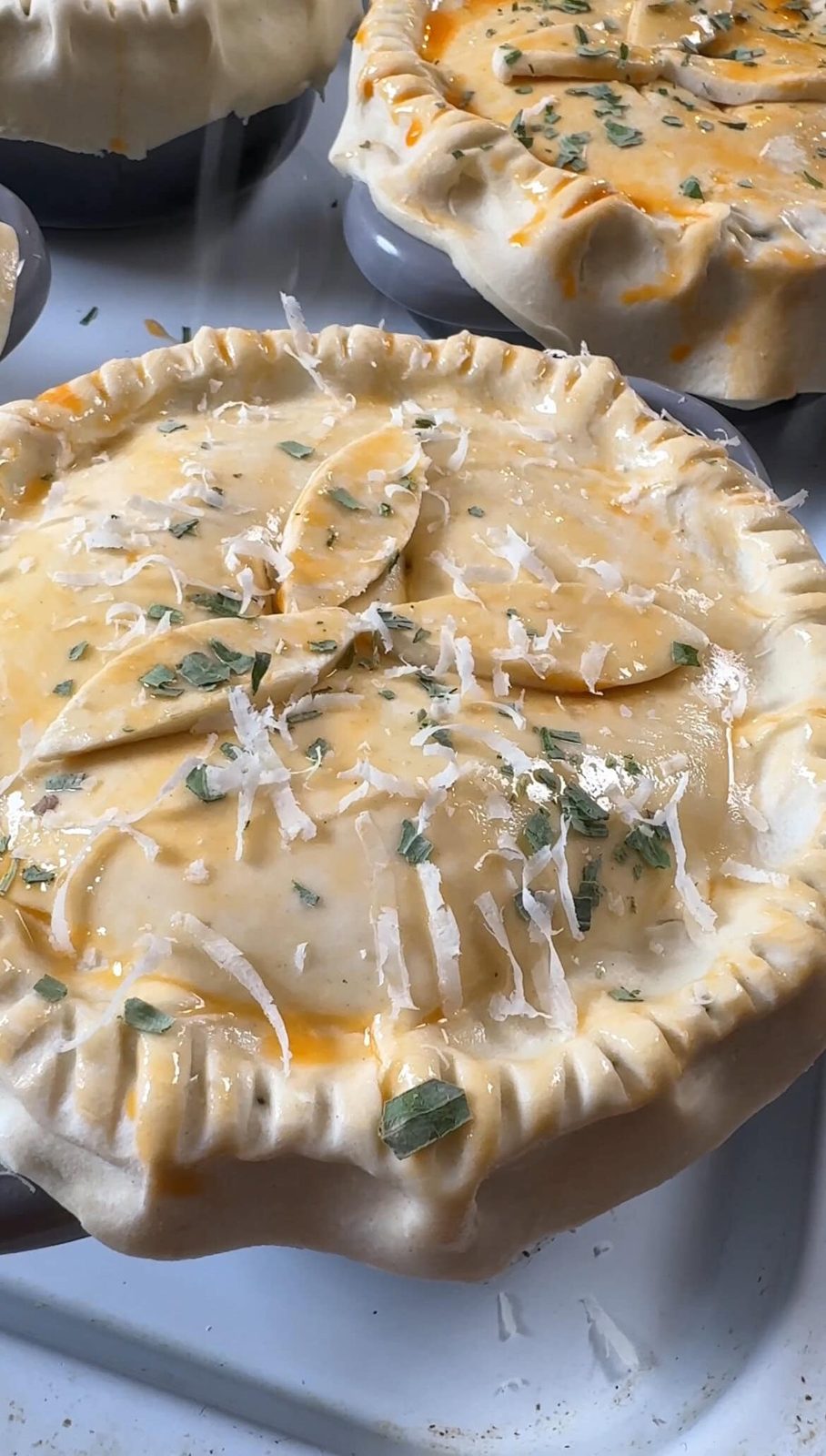 Parmesan and tarragon on top of unbaked mini chicken pot pie.
