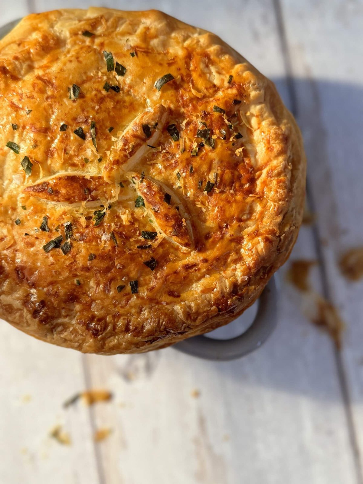 Mini chicken pot pie on white washed wood table.
