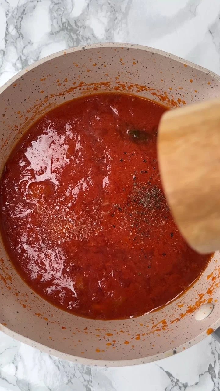 Making tomato sauce and mixing with spoon.