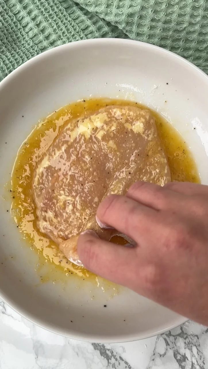 Covering the chicken breast in egg.