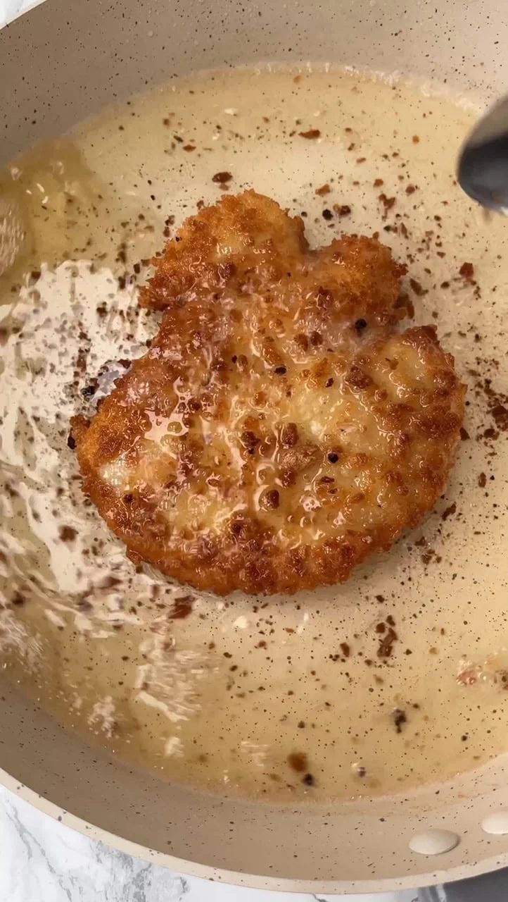 Frying breaded chicken breast in hot oil.