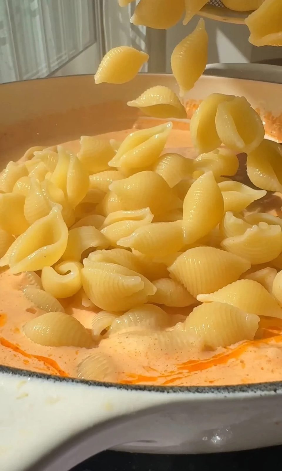 adding pasta to parmesan garlic sauce.
