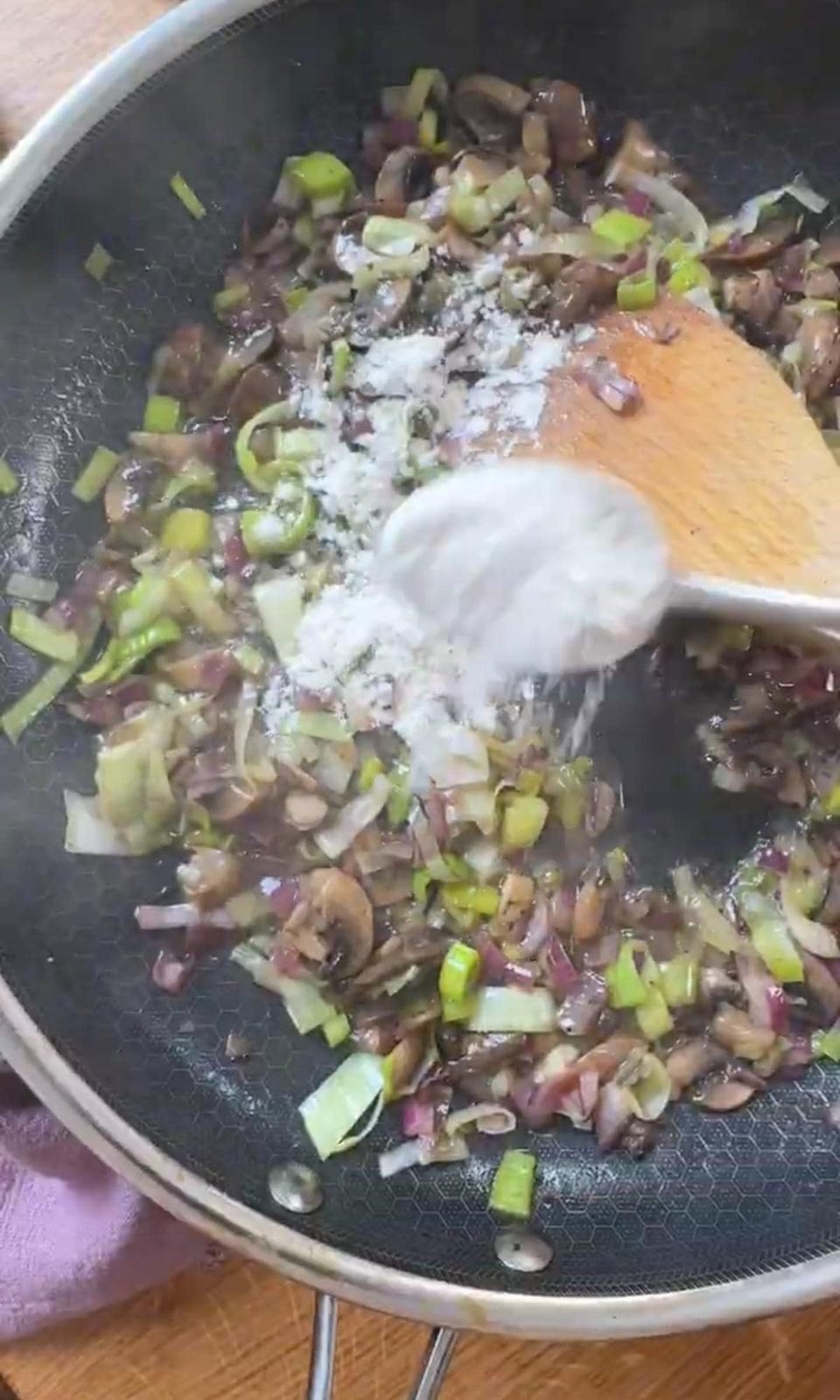 Adding flour to vegetables in pan to make a roux.