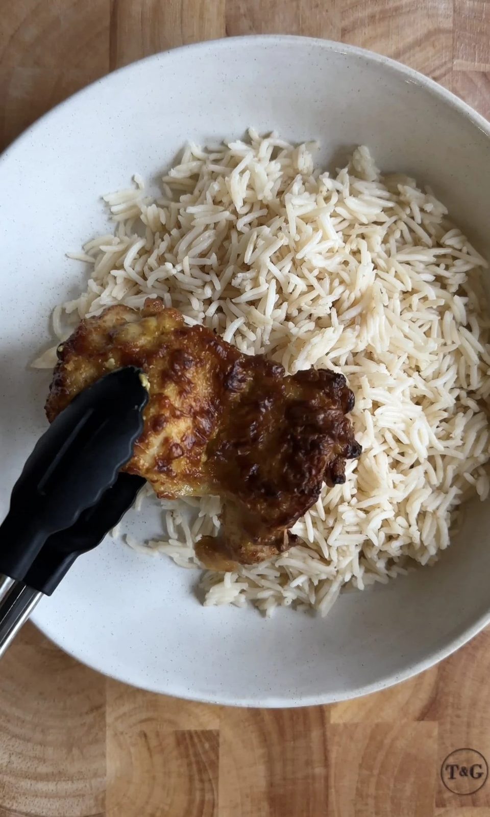 Adding chicken satay thighs to a bowl of rice.