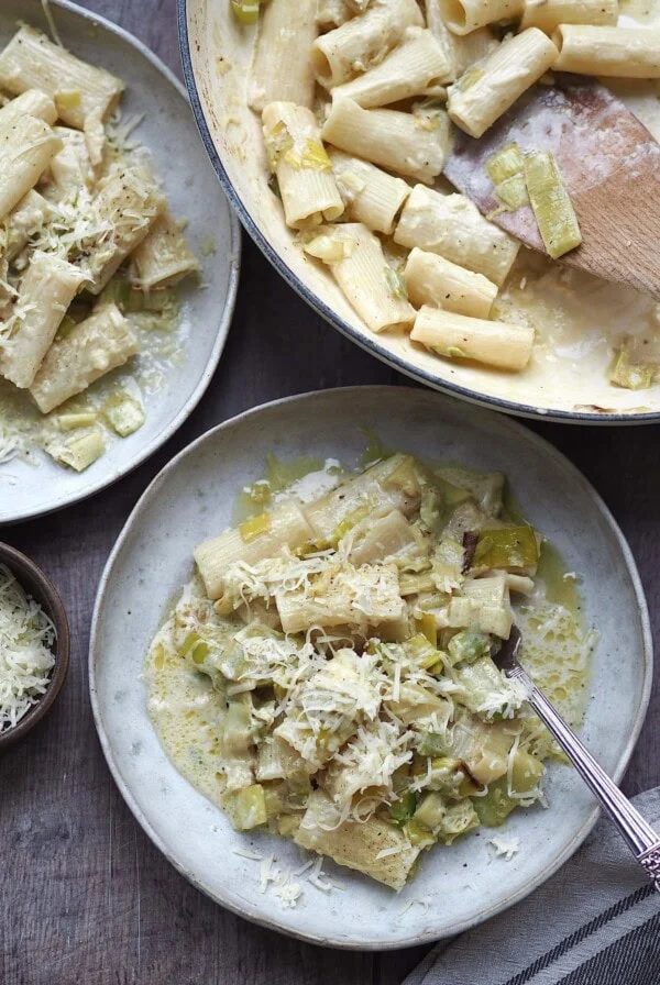 Caramelised Leek Pasta on a plate topped with grated cheese next to the cooking pan.