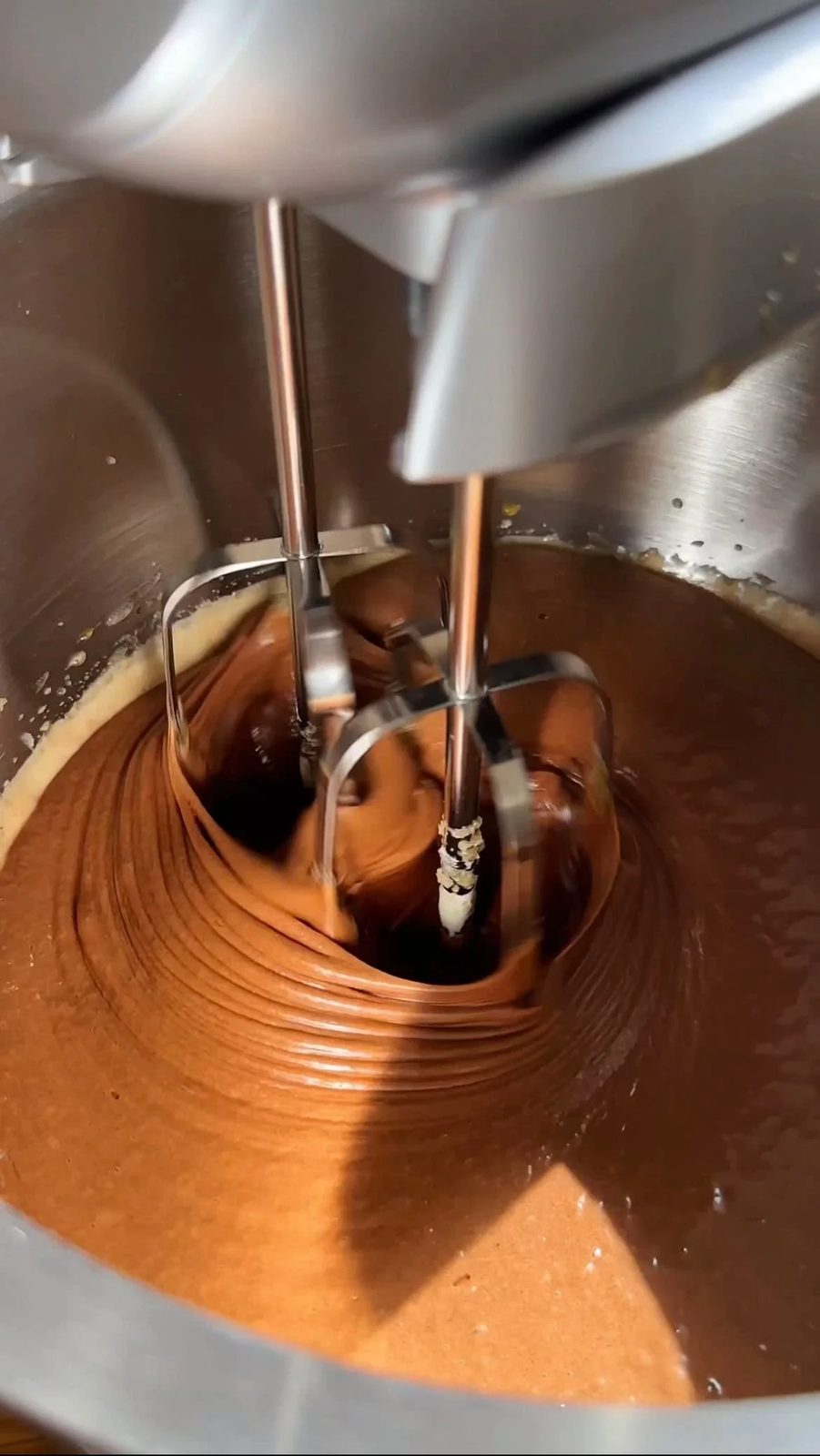 whisking the chocolate brownie batter with an electric mixer