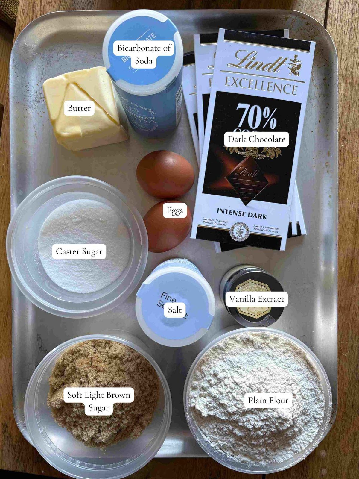 Chocolate, sugars, flour, butter, and other cookie ingredients on table.