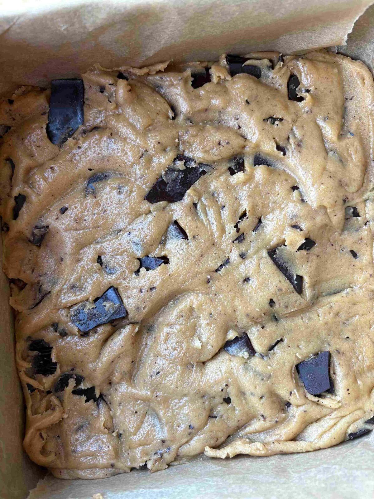 Pressing chocolate chip cookie bar dough into the pan.