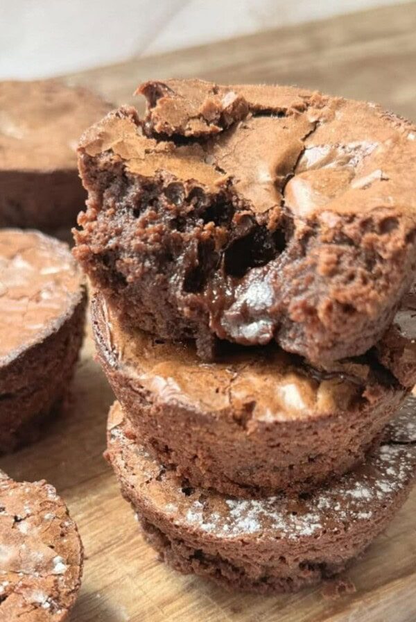 a stack of brownie bites on a wooden chopping board.