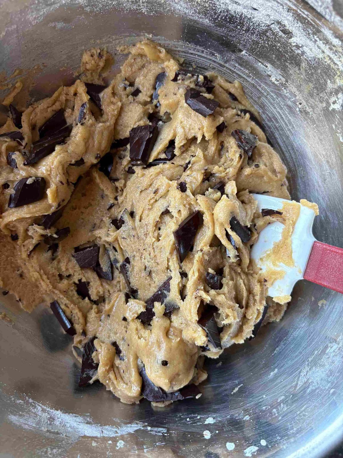 Adding chocolate to chocolate chip cookie bar dough.