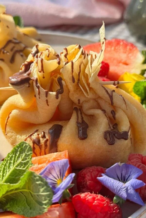 aumonieres de crepes on plate with nutella drizzled over the top.