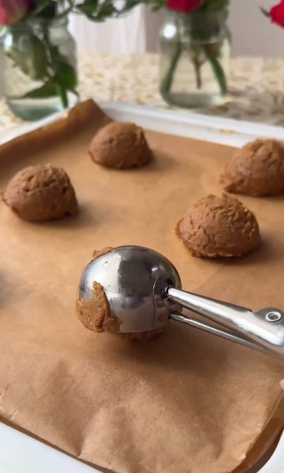 Scooping chocolate chipless cookie dough onto parchment paper.