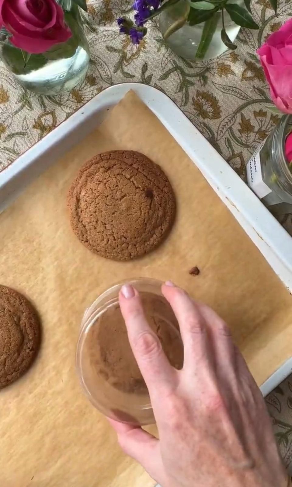 Reshaping baked chocolate chipless cookies with glass.