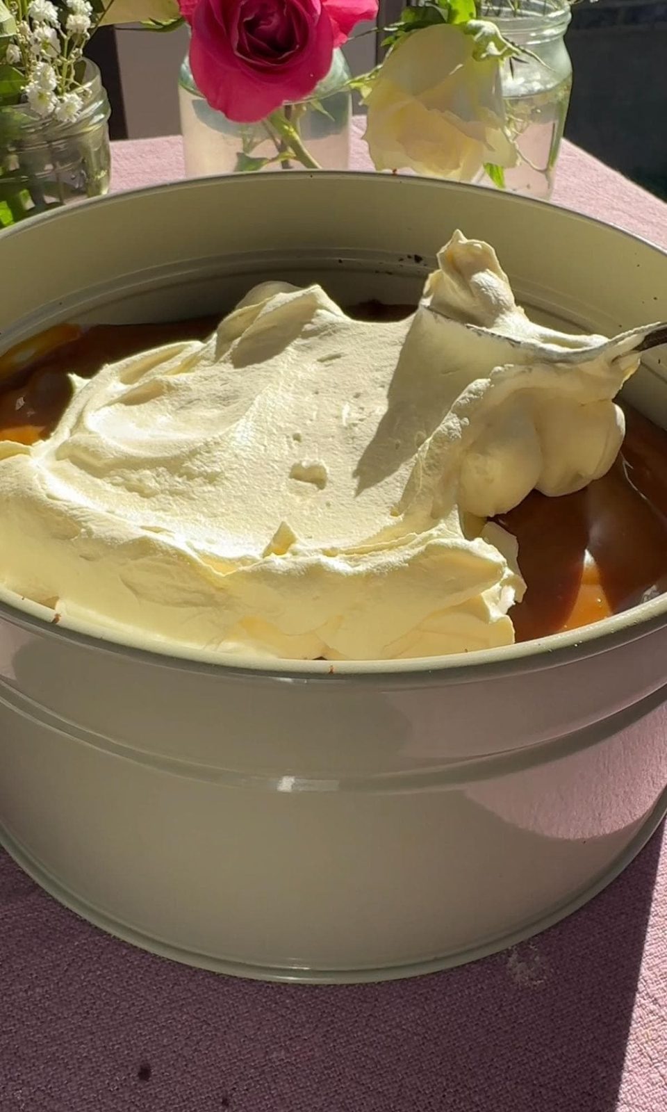 Adding whipped cream to chocolate cake in the pan.