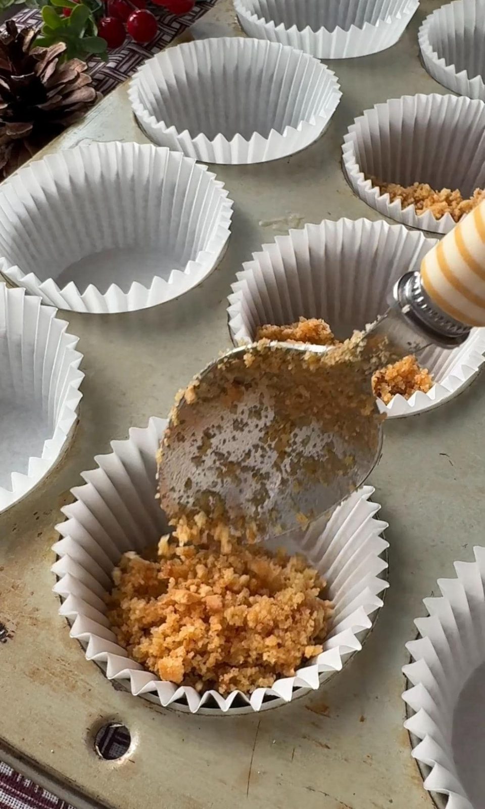 Adding biscuit base to muffin liners.