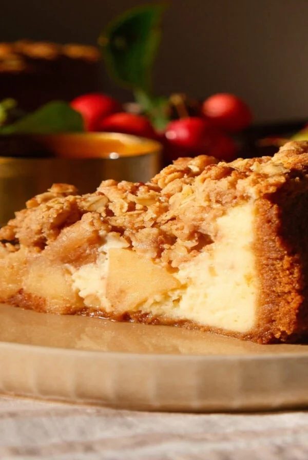 Slice of apple crumble cheesecake on a beige plate.