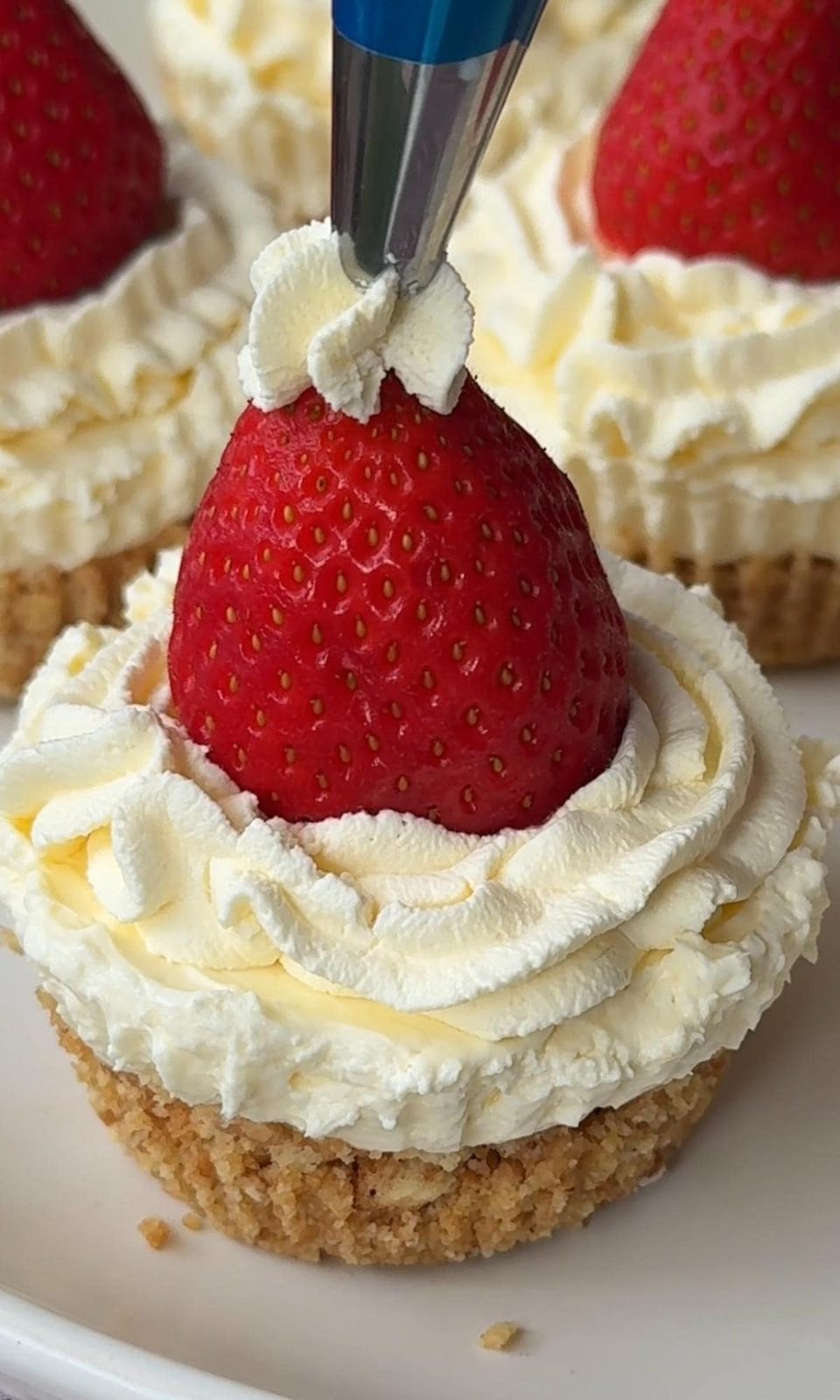 Topping Christmas cheesecakes with Santa hat decoration.