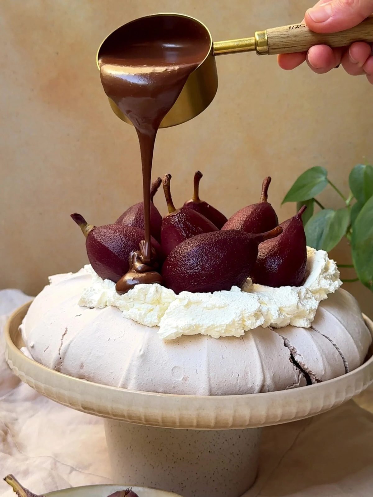 Pouring chocolate sauce over Christmas Pavlova with poached pears.