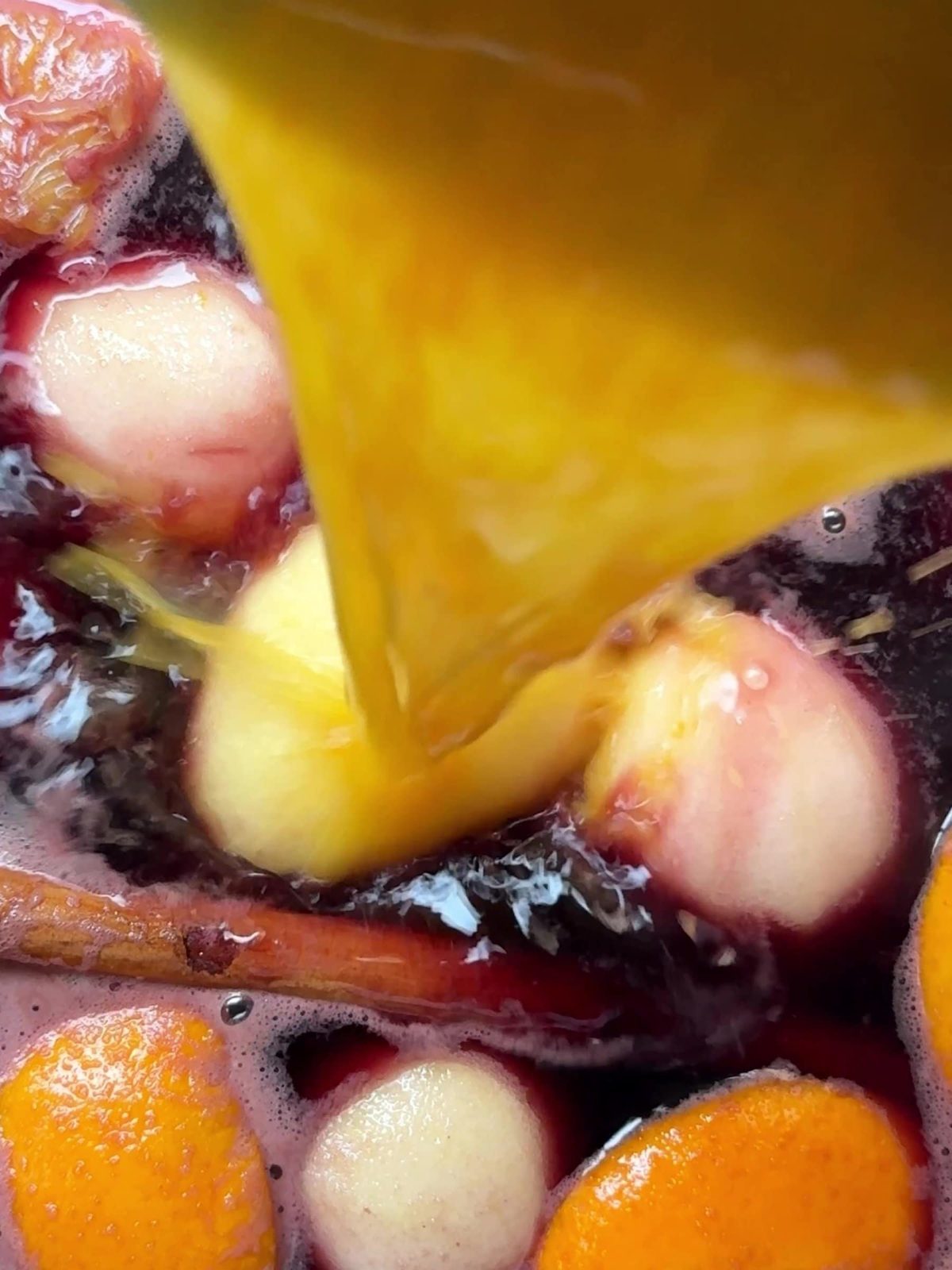 Adding orange juice to red wine to poach pears.
