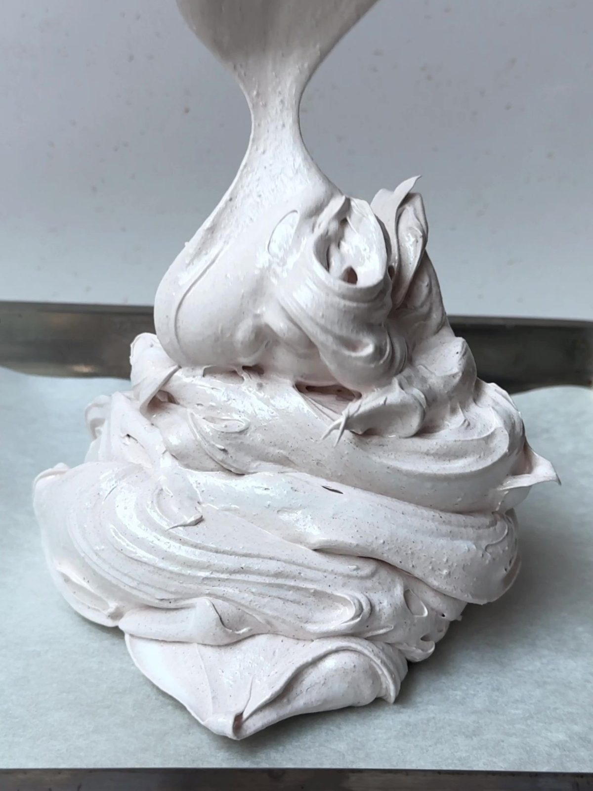 Adding a pile of merengue to a baking sheet.