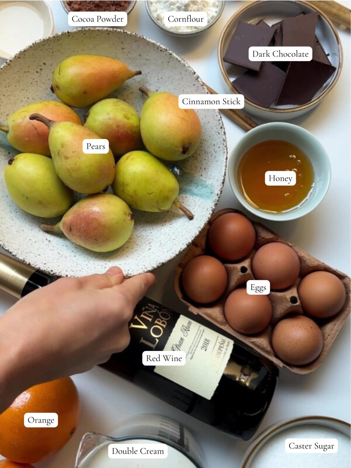 Pears, eggs, chocolate, wine, and honey ingredients for pavlova.