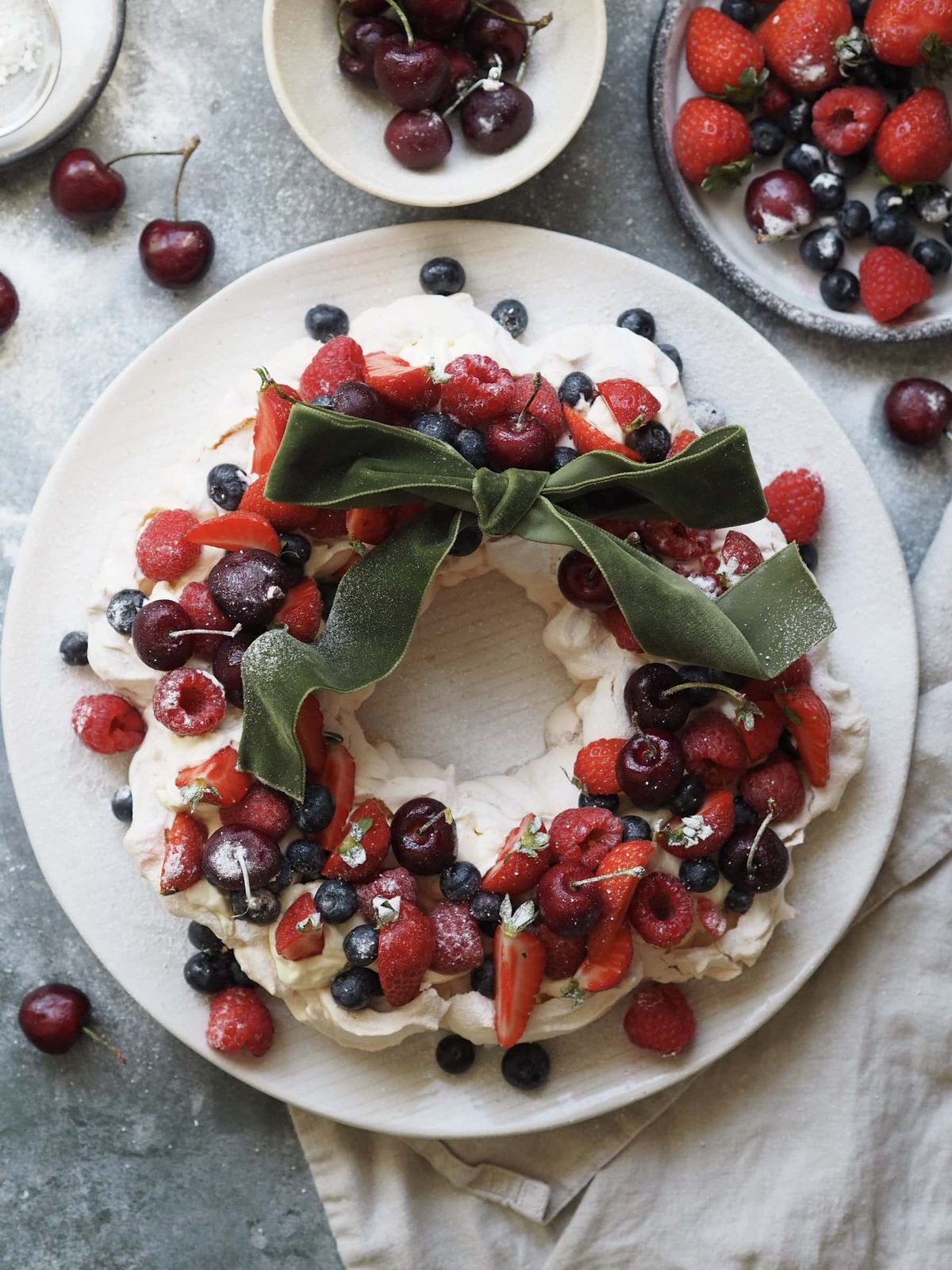 Christmas Pavlova on a plate with berries and cherries.