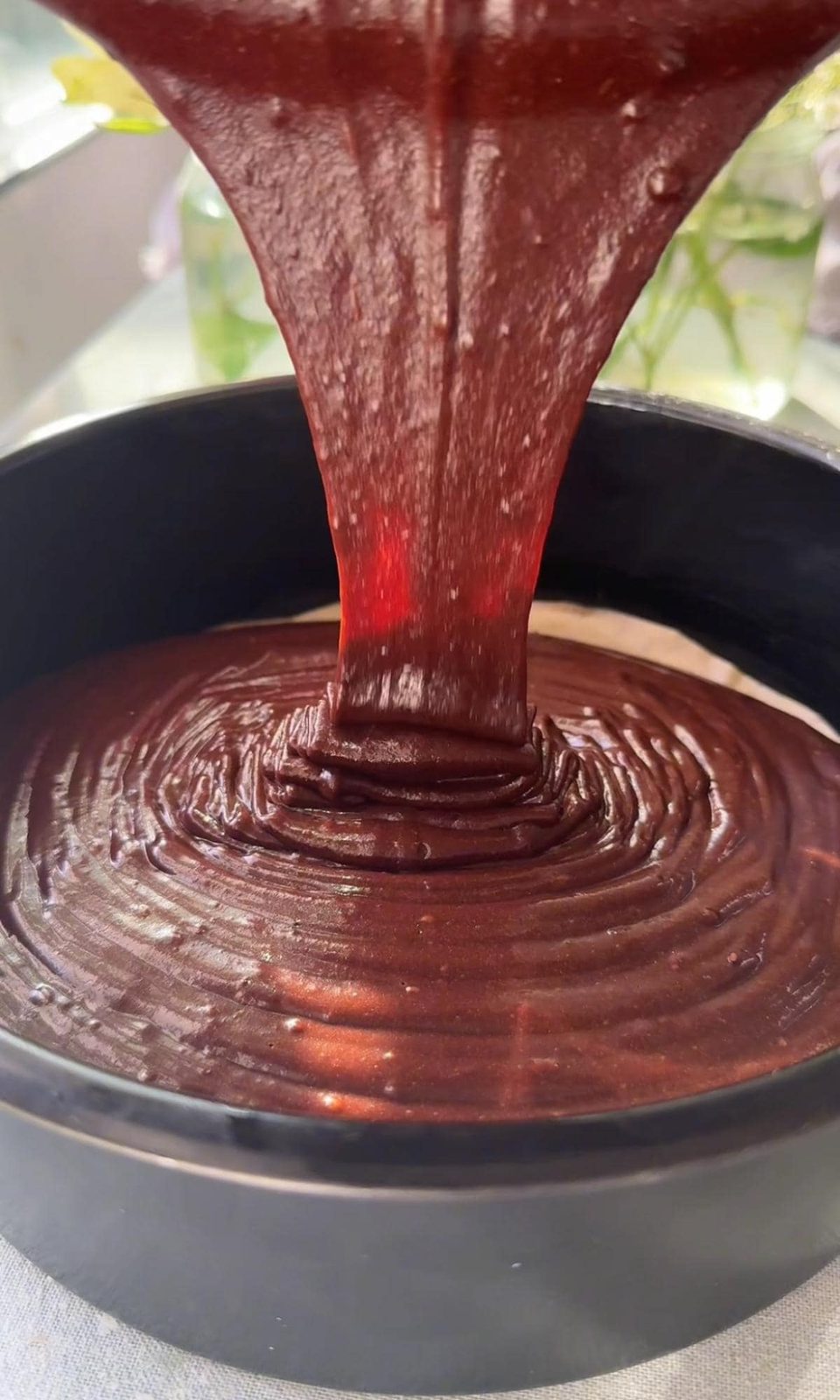 pouring chocolate cake into the tin.