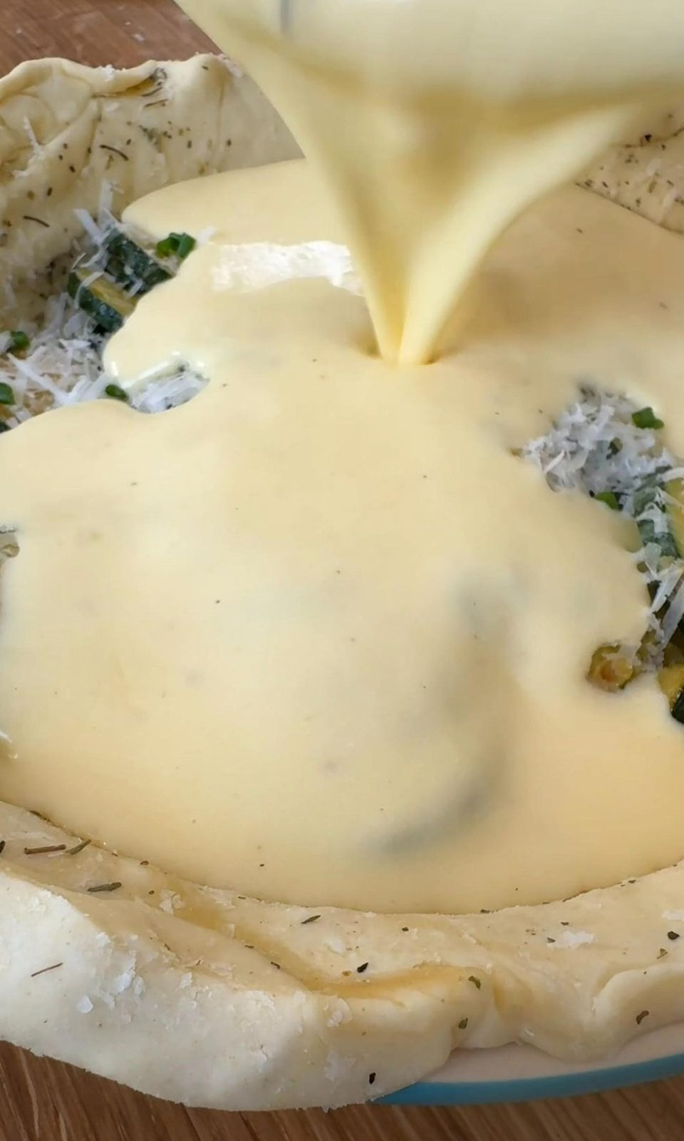 adding eggs and cream to the quiche.