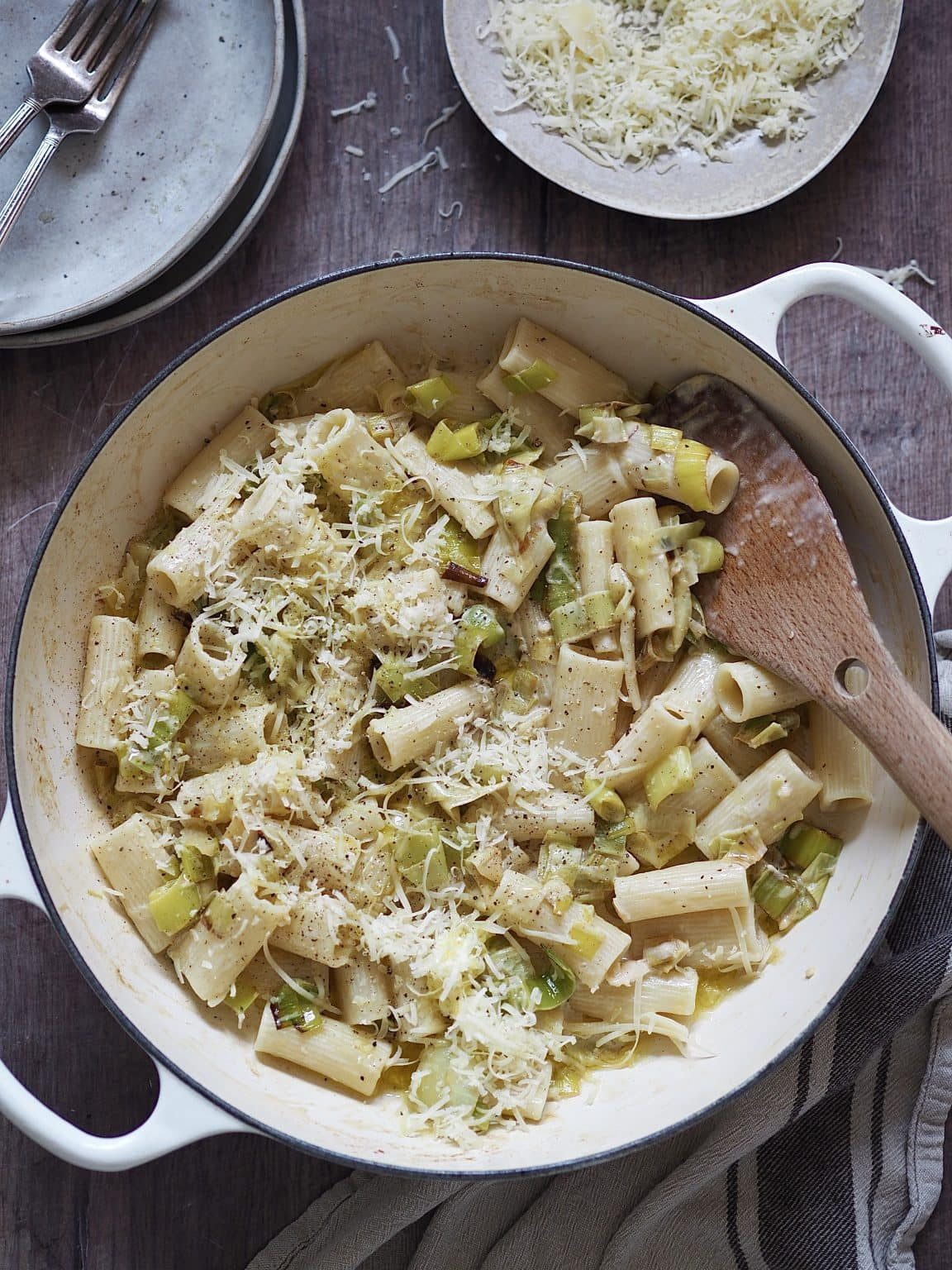 White shallow casserole dish of rigatoni tossed with cream and caramalised leeks and topped with grated cheese.