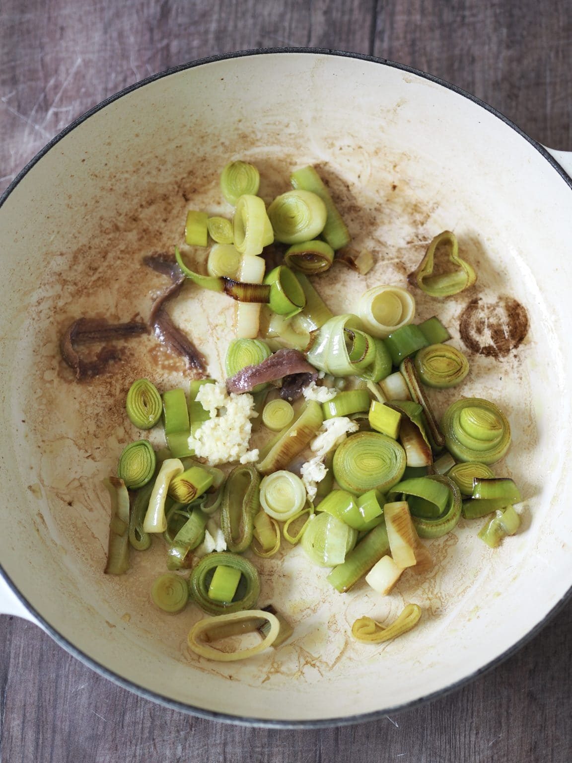 Garlic being added to slow cooked leeks in a shallow casserole.