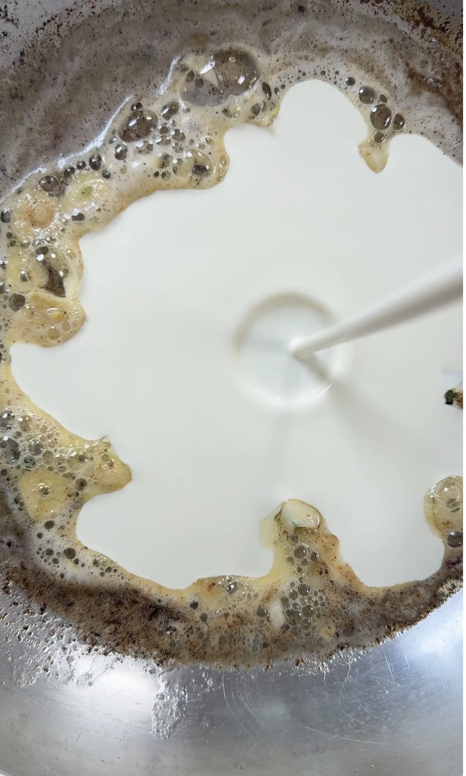 Adding cream to make a sauce for creamy chicken pasta.