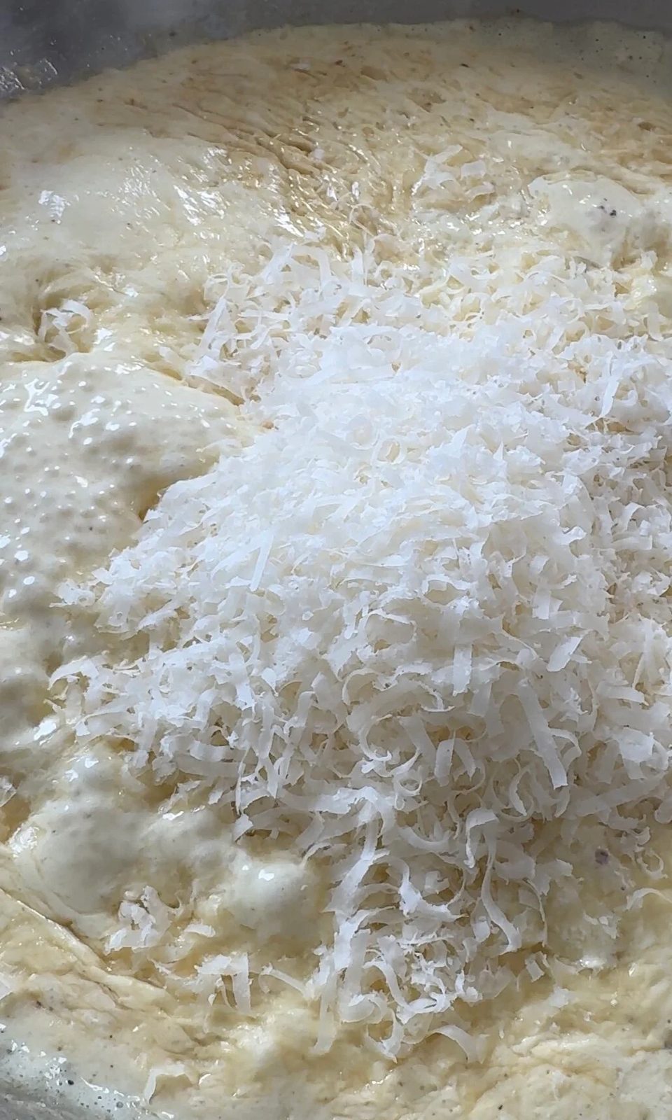 adding parmesan to the creamy chicken sauce.
