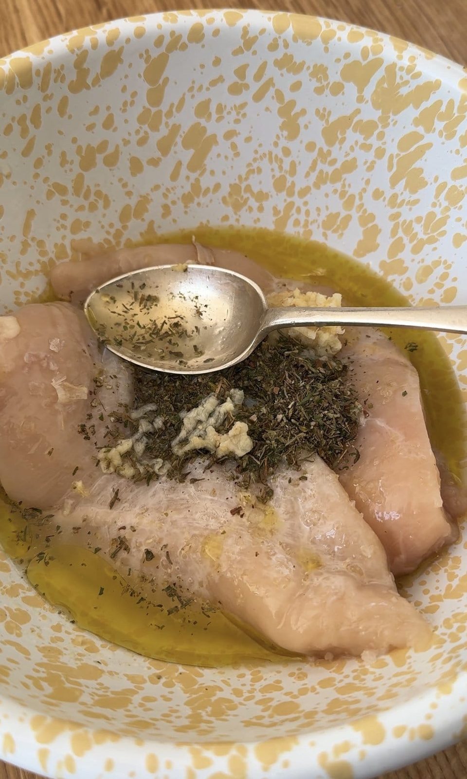 Marinating chicken breasts in herbs and oil.
