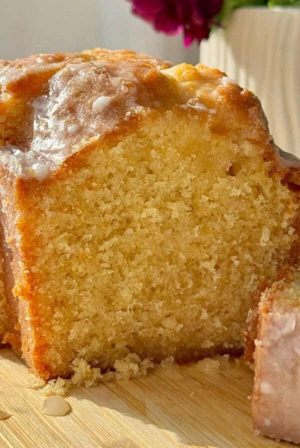 Sliced lemon loaf cake on wooden board.