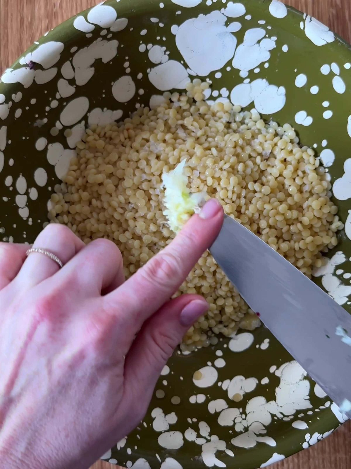 Adding garlic to giant couscous.