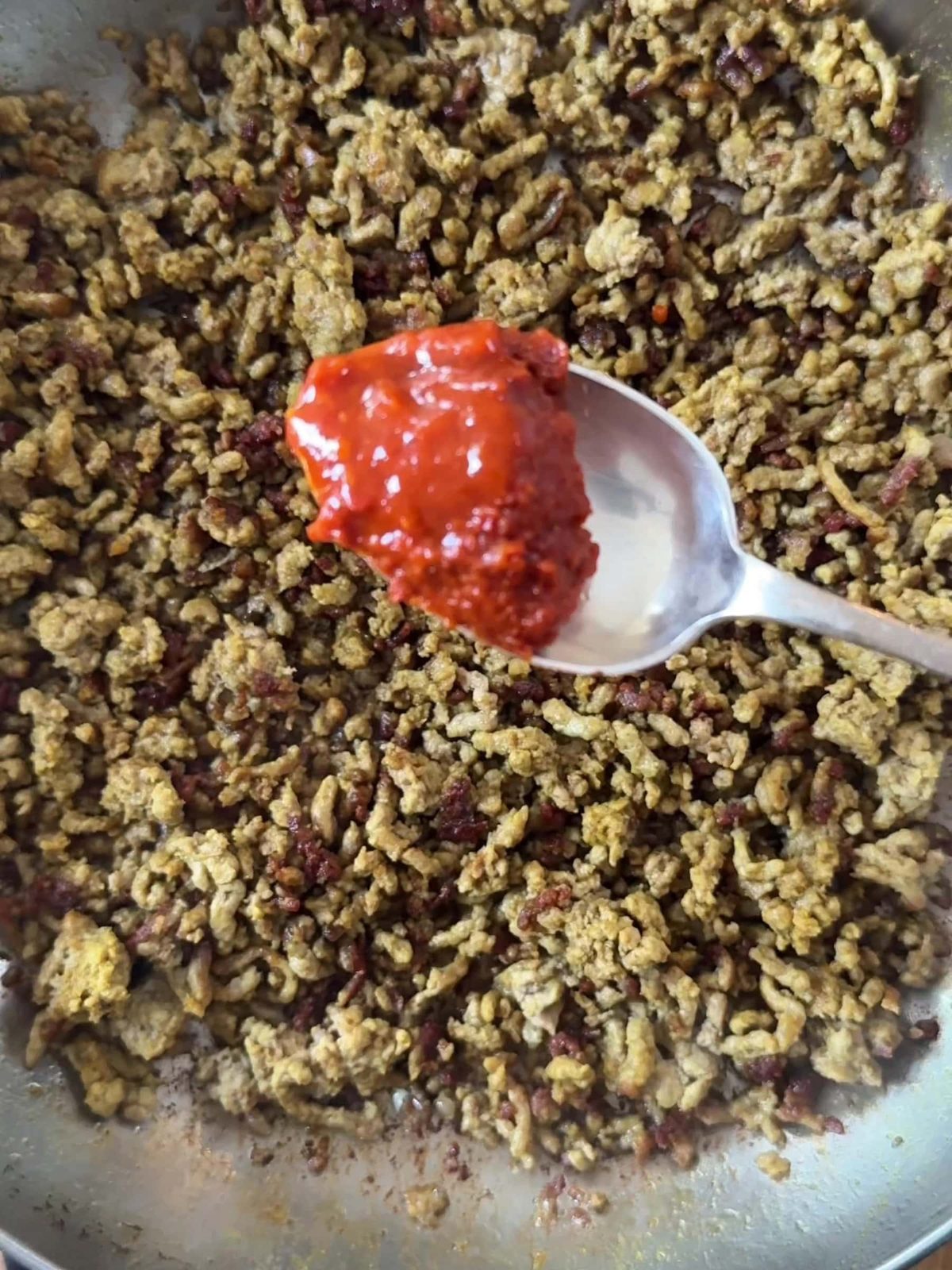 Stirring in harissa paste to mince.