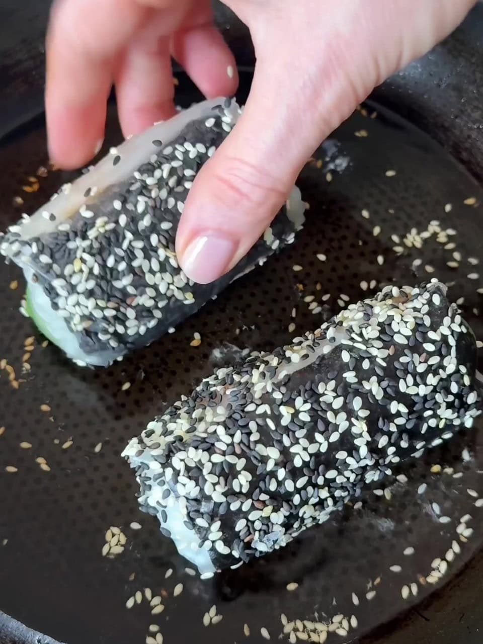 Rolling rolls in sesame seeds.