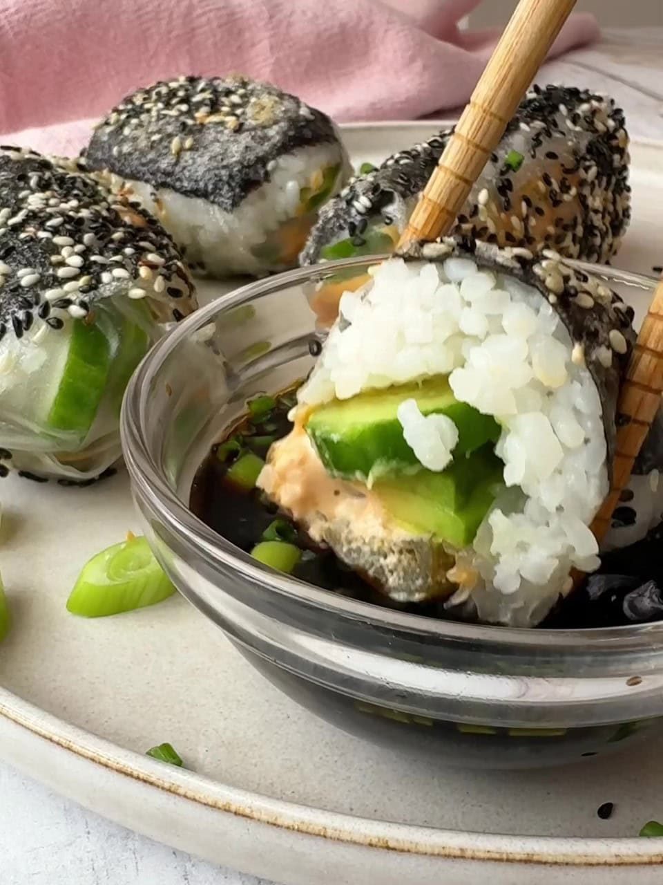 Dipping crispy rice paper rolls in sauce with chopsticks.