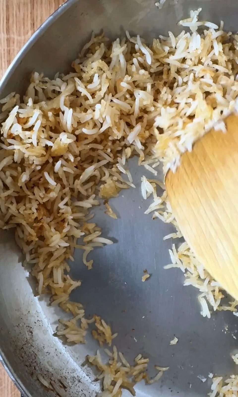 frying day old rice in a silver pan.