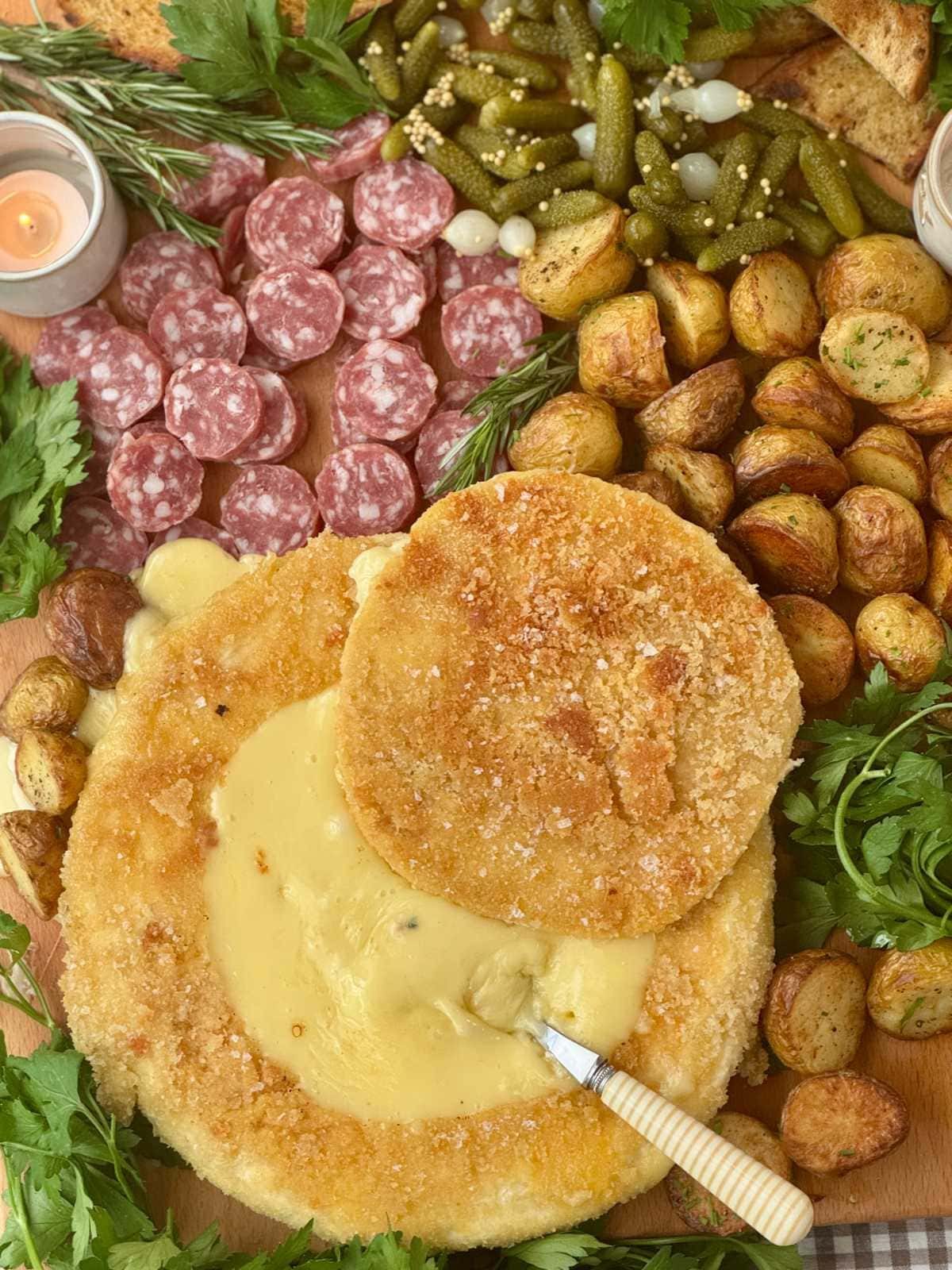 deep fried brie with a spoon on a charcuterie board.
